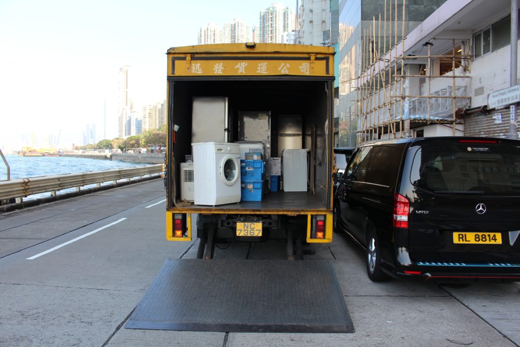 A washing machine in the back of a truck with other appliances