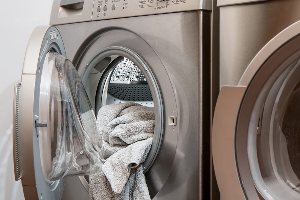 Washing machine with open door and towels hanging out