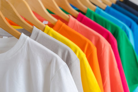 Close up of Colorful t-shirts on hangers, apparel background.