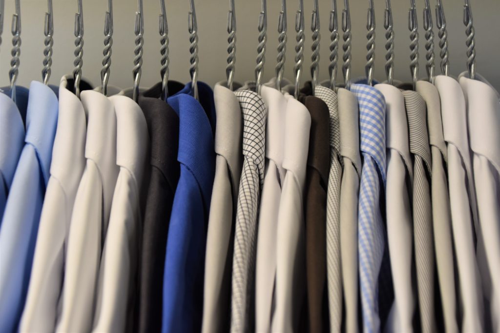 Brightened clothes hanging neatly in a closet.